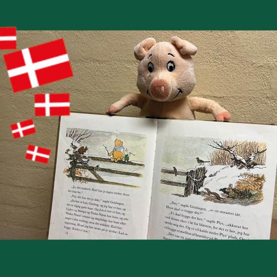 Foto af en lille tøjgris med en opslået Peter Plys bog