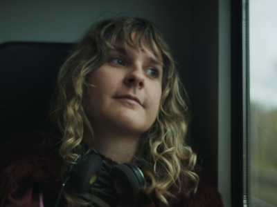 Kvinde sidder i tog og kigger eftertænksomt