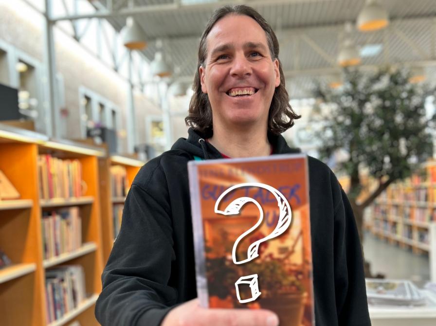 Kenneth står på Hovedbiblioteket. Han holder romanen "Gud taler ud" af Jens Blendstrups foran sig og smiler til kameraet. Bogforsiden er let sløret og der er sat et stort hvidt spørgsmålstegn henover. Bag Kenneth ses biblioteksrummet med fyldte bogreoler og bogudstillinger.