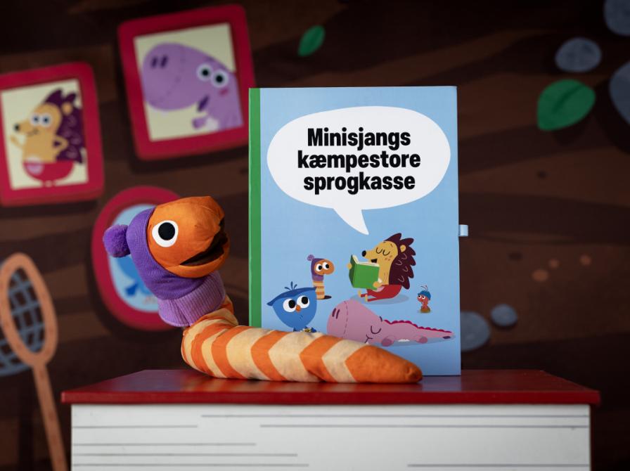 Orm fra DR Minisjangs Børste-univers sidder på en stor børn sammen med Minisjangs kæmpestore sprogkasse